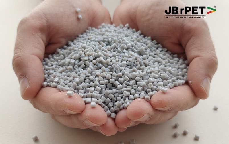 Cupped hands holding grey recycled PET resin pellets